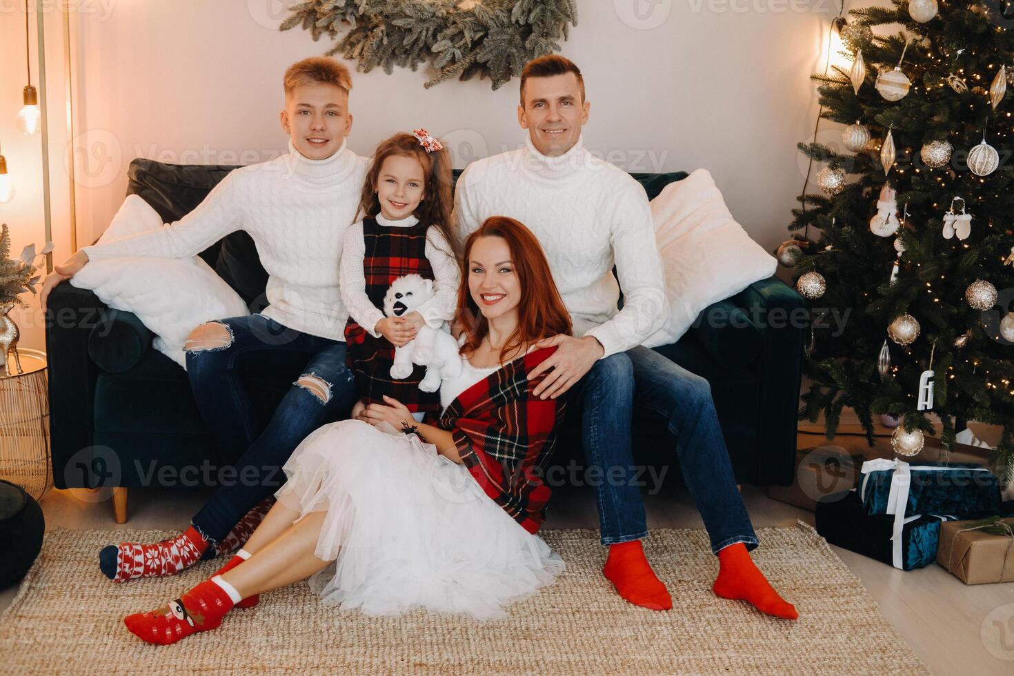 Close-up portrait of a happy family sitting on a sofa near a Christmas tree celebrating a holiday photo