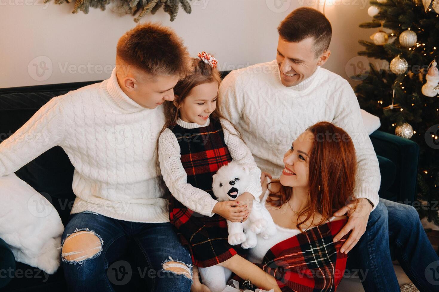 Close-up portrait of a happy family sitting on a sofa near a Christmas tree celebrating a holiday photo