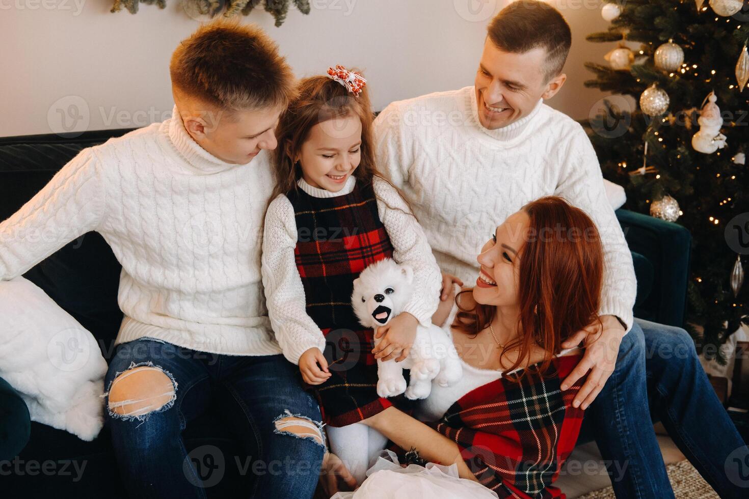 Close-up portrait of a happy family sitting on a sofa near a Christmas tree celebrating a holiday photo