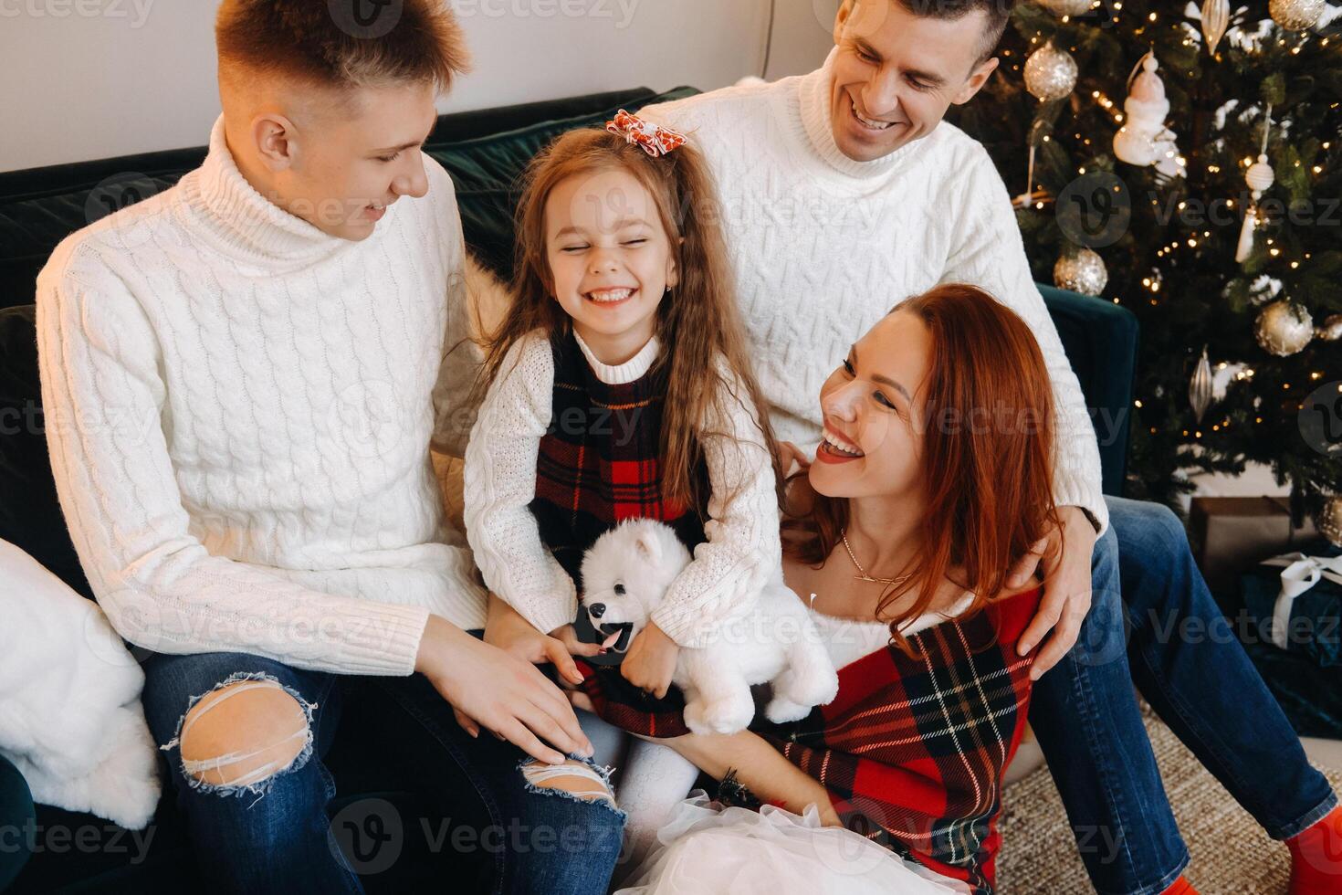 Close-up portrait of a happy family sitting on a sofa near a Christmas tree celebrating a holiday photo