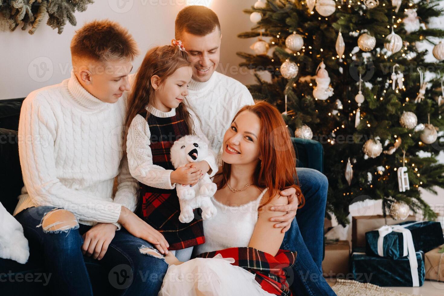 Close-up portrait of a happy family sitting on a sofa near a Christmas tree celebrating a holiday photo