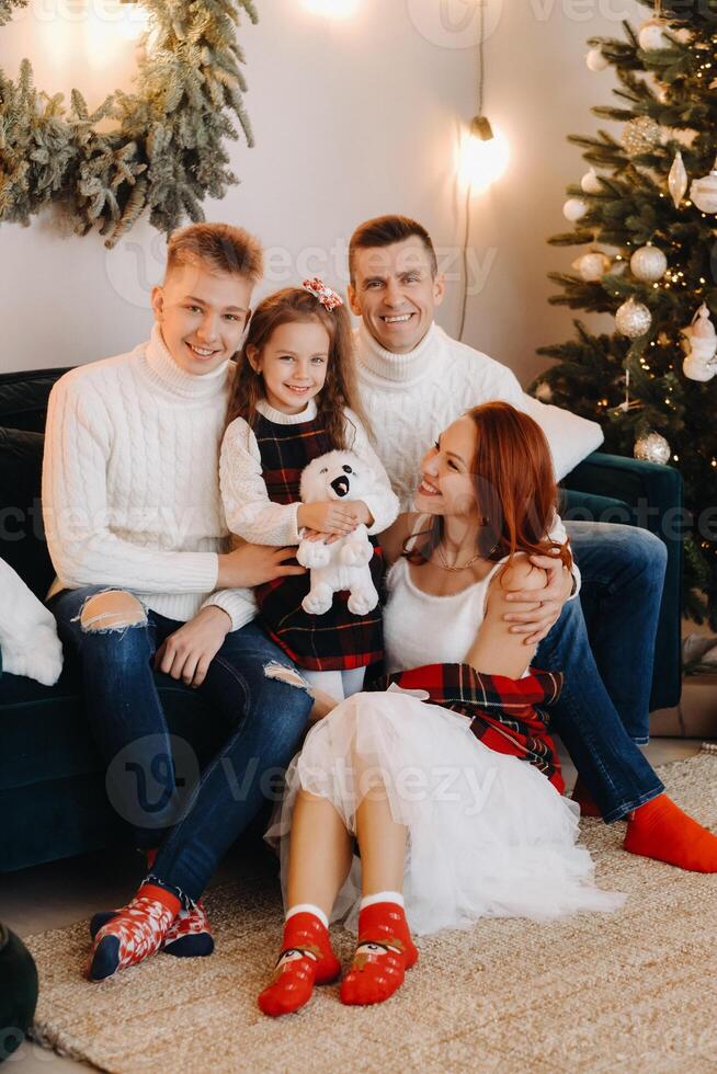 Close-up portrait of a happy family sitting on a sofa near a Christmas tree celebrating a holiday photo