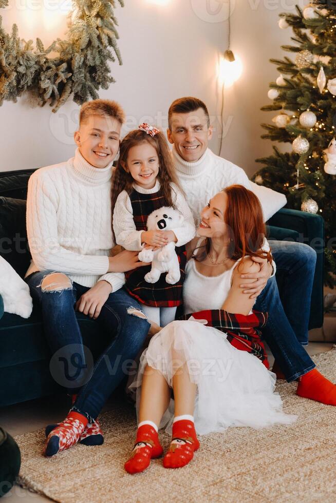 Close-up portrait of a happy family sitting on a sofa near a Christmas tree celebrating a holiday photo