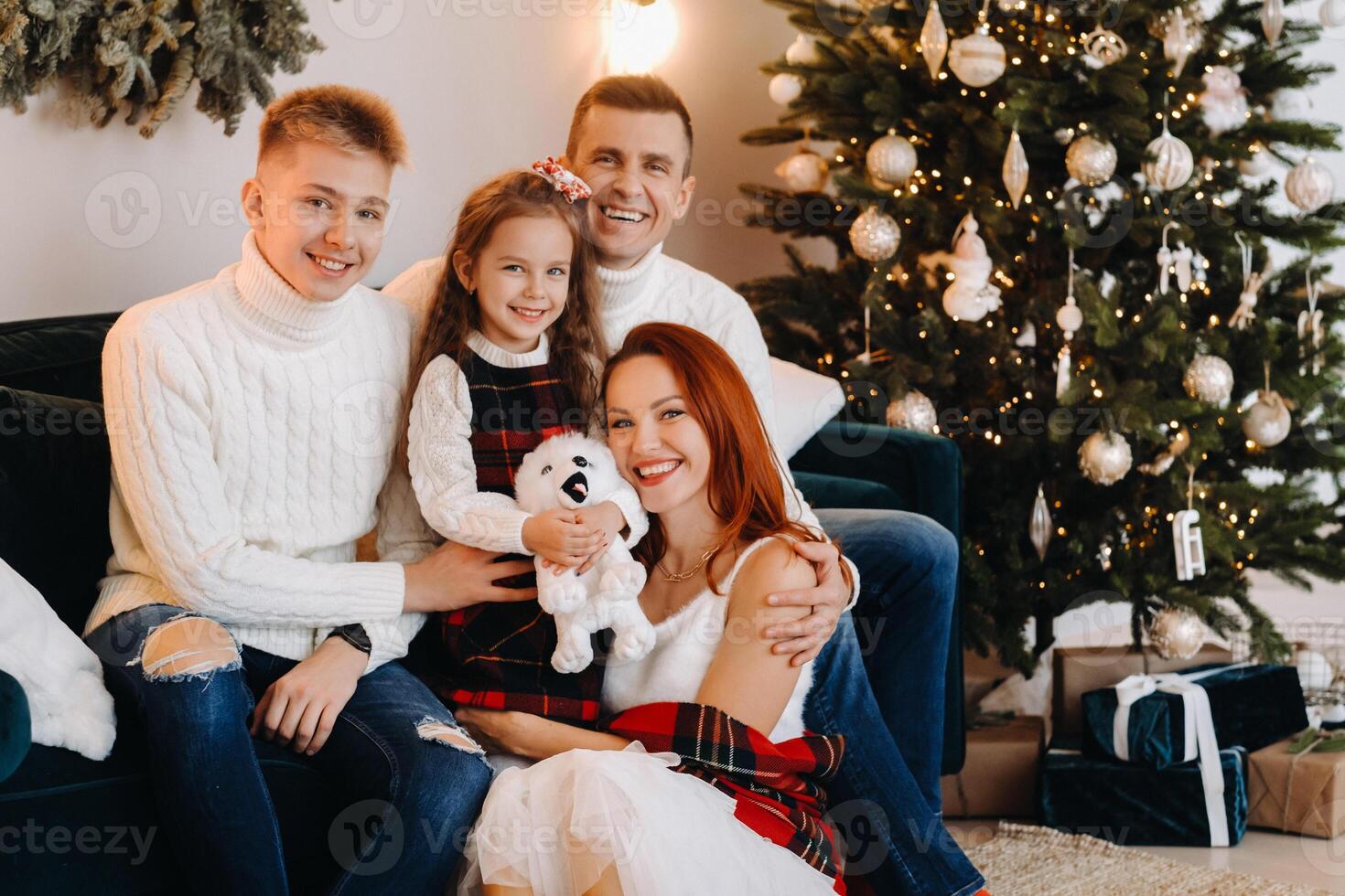 Close-up portrait of a happy family sitting on a sofa near a Christmas tree celebrating a holiday photo