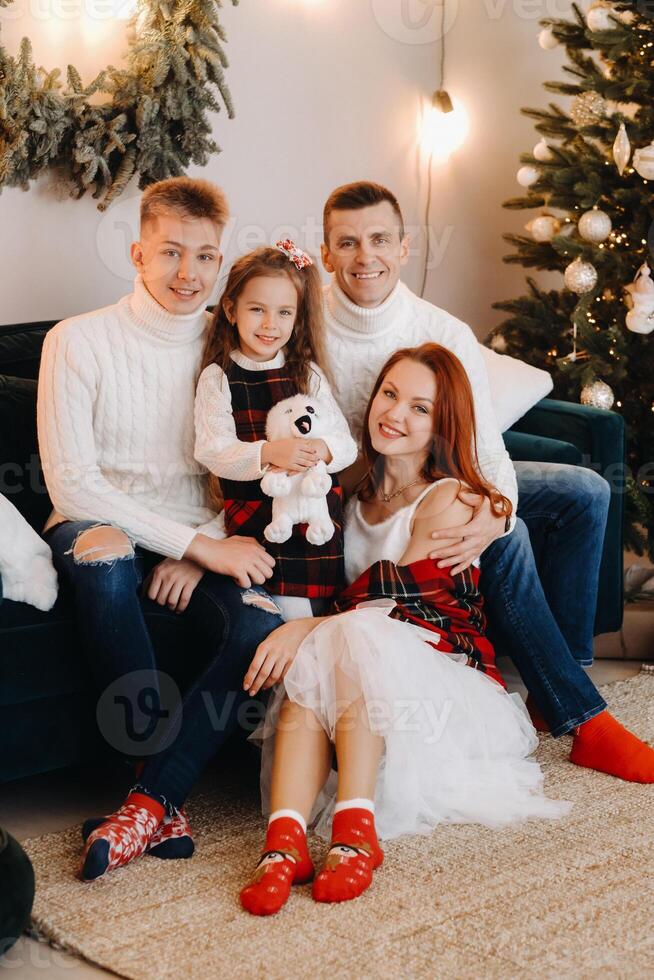Close-up portrait of a happy family sitting on a sofa near a Christmas tree celebrating a holiday photo