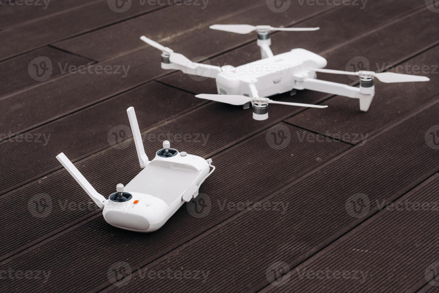 The remote control with the quadcopter is white, and the quadcopter itself is on a wooden background.flight controller on an old wooden background. The view from the top, photo