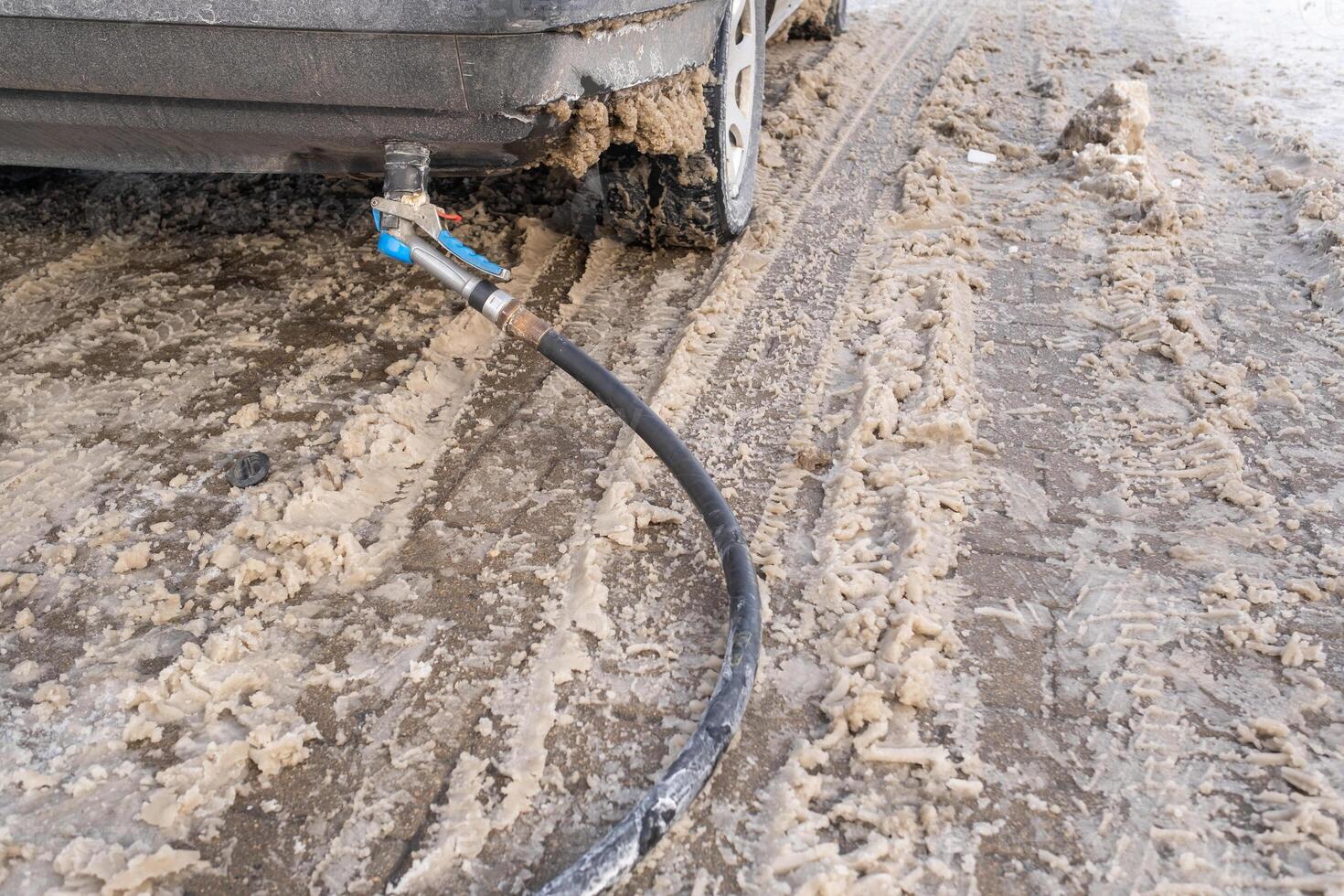 Filling the car from the bottom of the bumper with gas in the winter at the gas station photo
