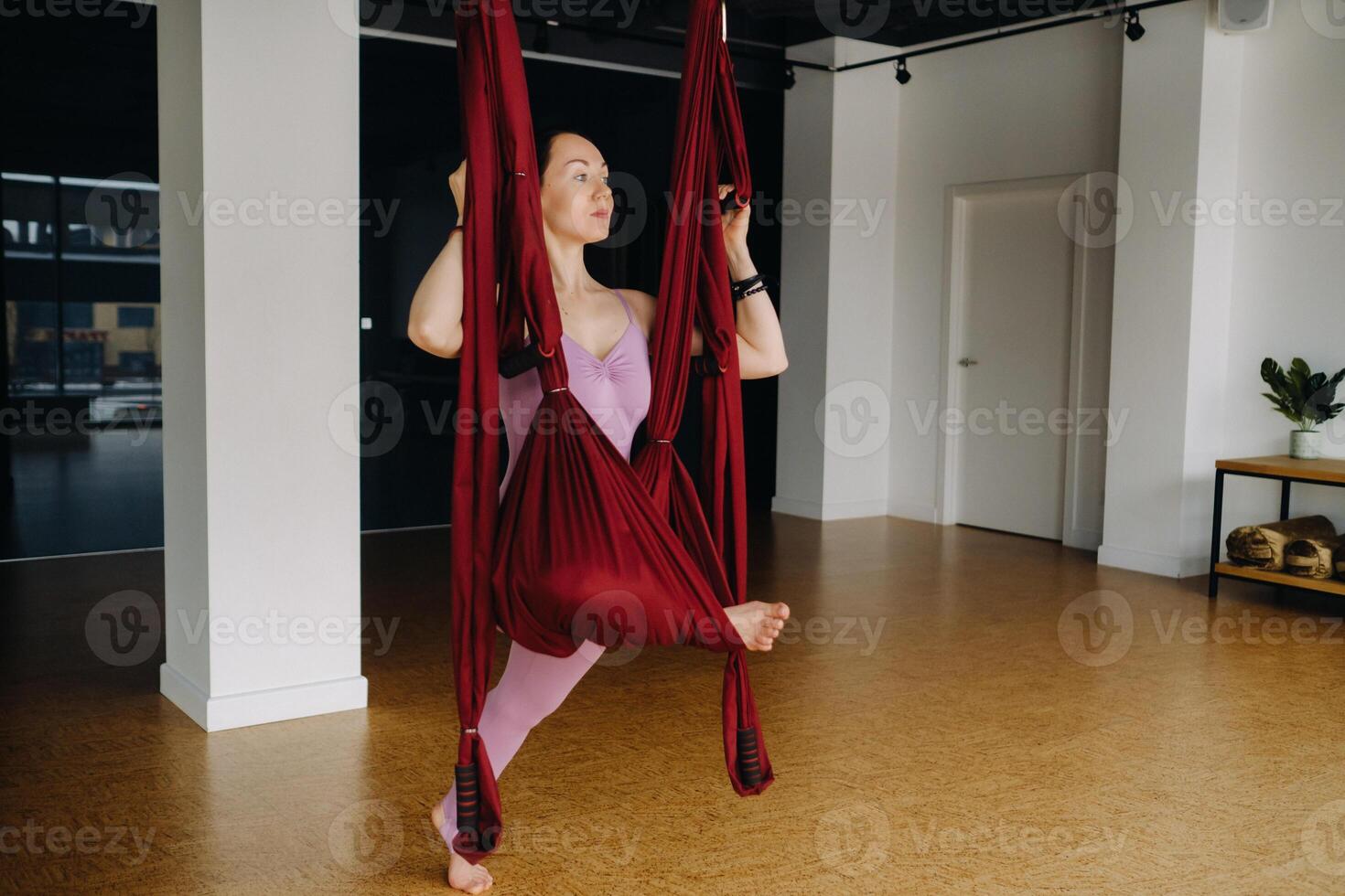 The girl is engaged in aerial yoga, doing stretching exercises on a hammock in the gym photo