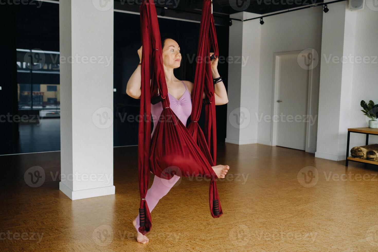 The girl is engaged in aerial yoga, doing stretching exercises on a hammock in the gym photo