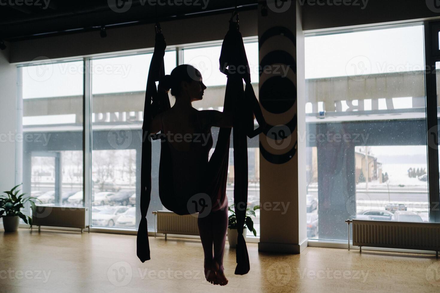 The girl is sitting in a hanging hammock and doing yoga in the gym photo