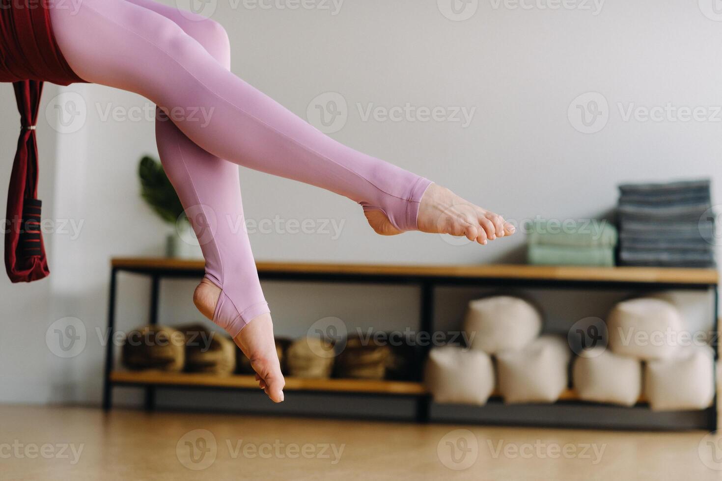 close-up of the legs of a girl sitting in a hanging hammock and doing yoga in the gym photo