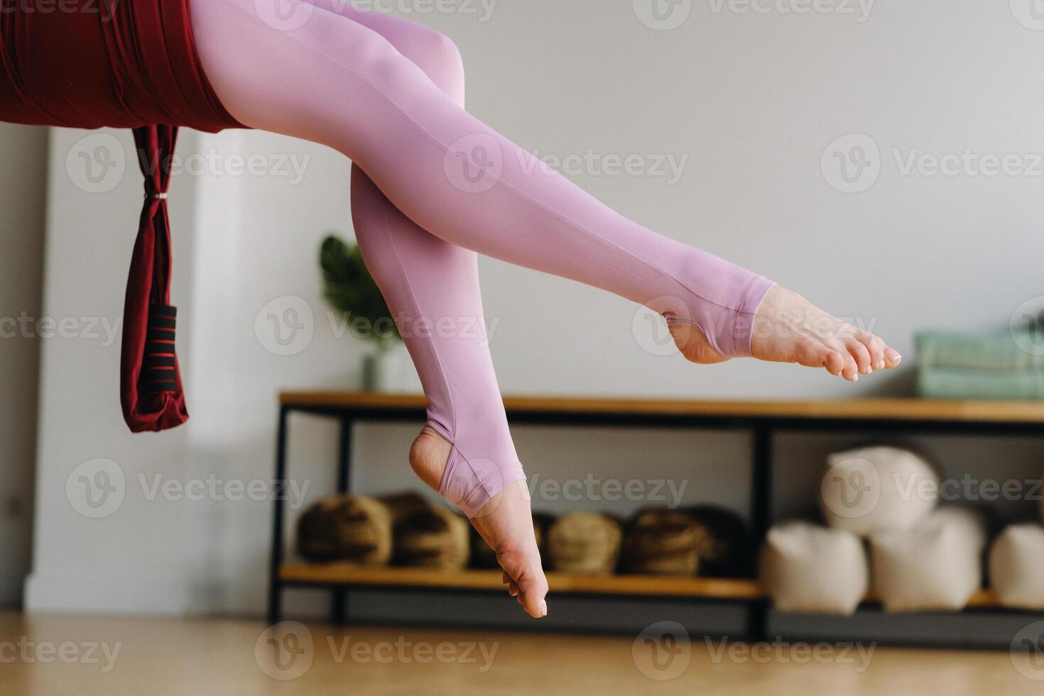close-up of the legs of a girl sitting in a hanging hammock and doing yoga in the gym photo