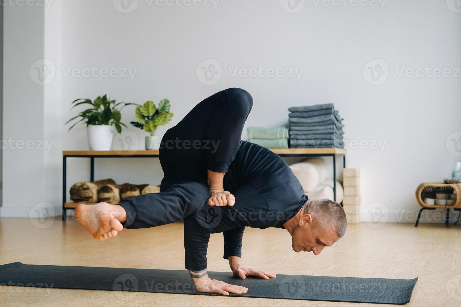 An athletically built man does yoga in the gym on a mat photo