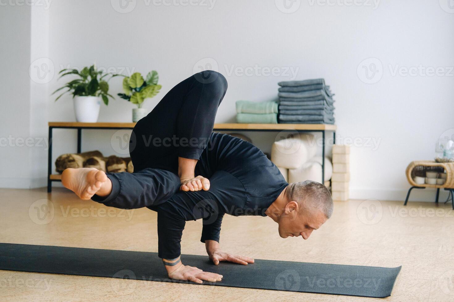 An athletically built man does yoga in the gym on a mat photo