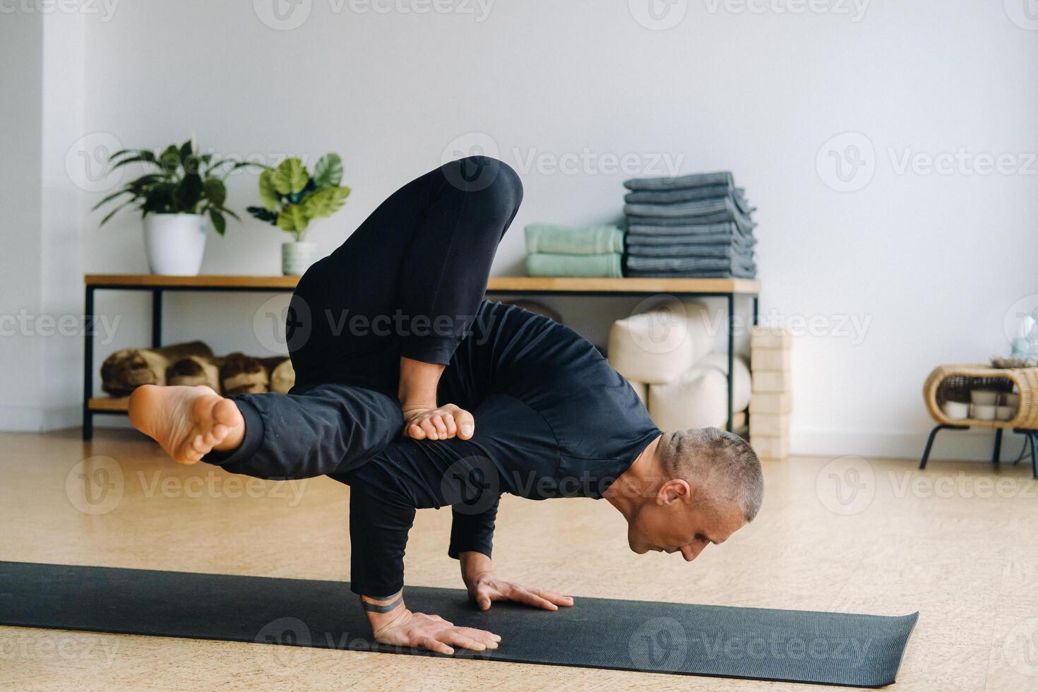 An athletically built man does yoga in the gym on a mat photo