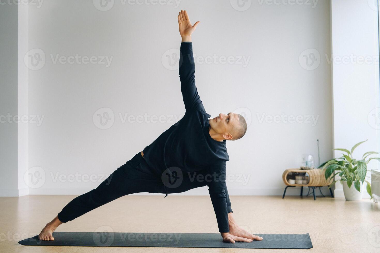 An athletically built man does yoga in the gym on a mat photo