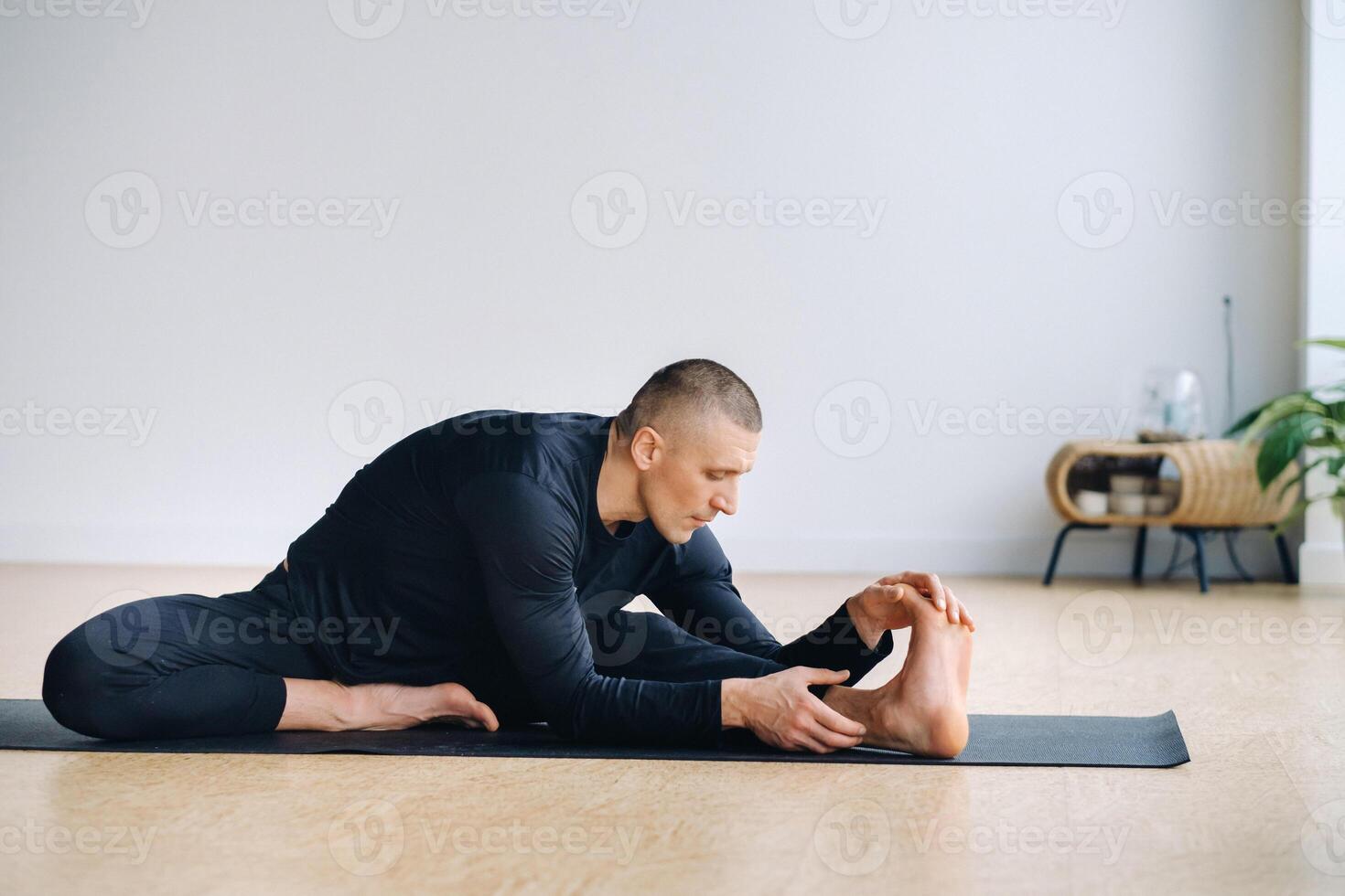 An athletically built man does yoga in the gym on a mat photo