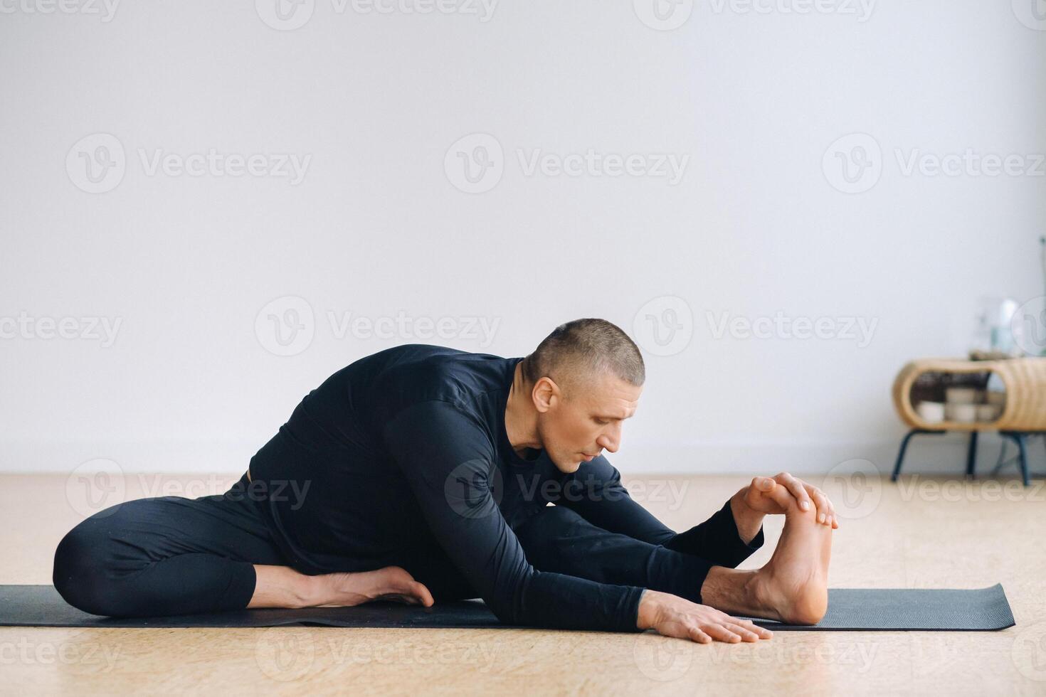 An athletically built man does yoga in the gym on a mat photo