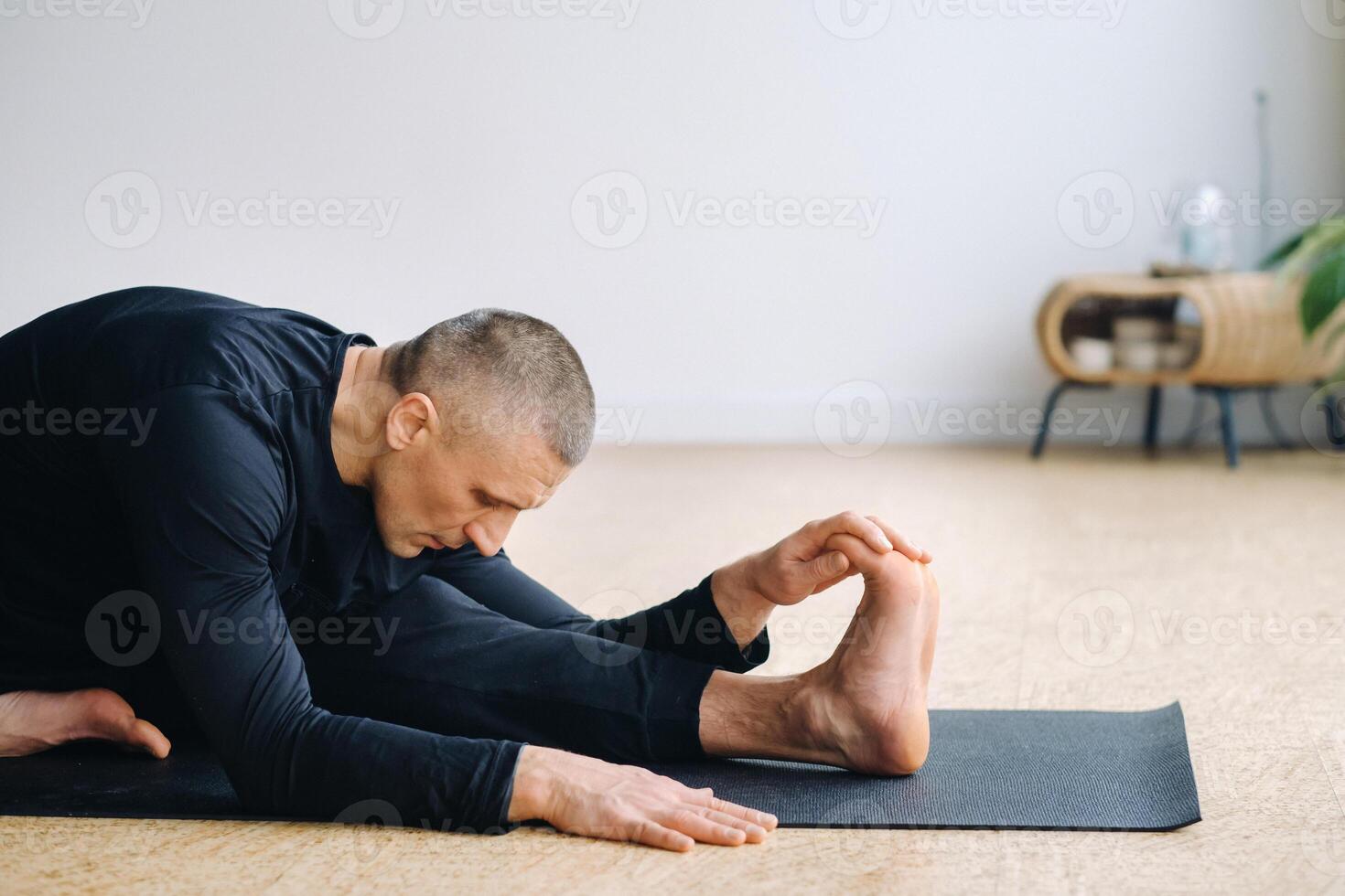 An athletically built man does yoga in the gym on a mat photo