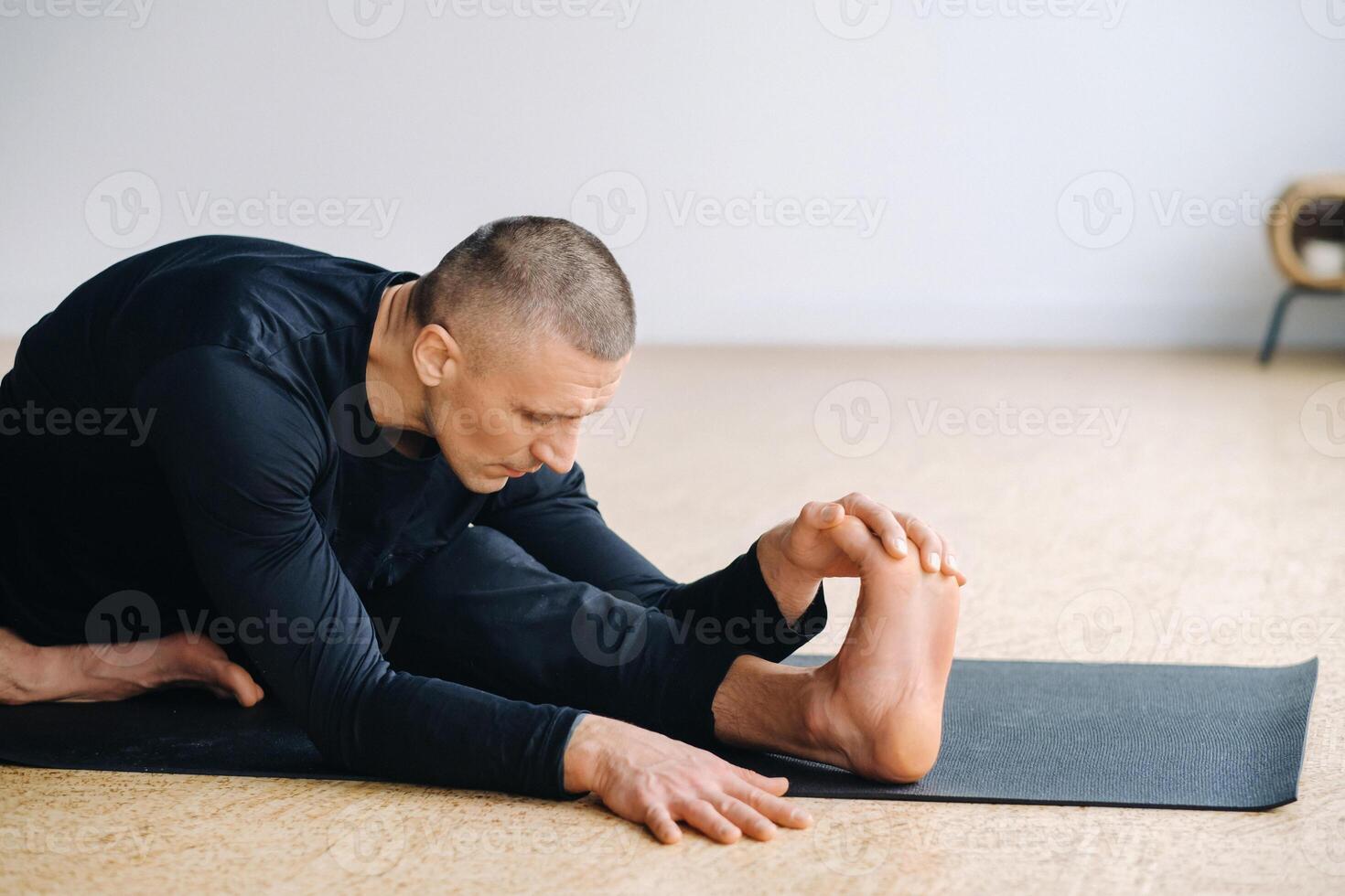 An athletically built man does yoga in the gym on a mat photo