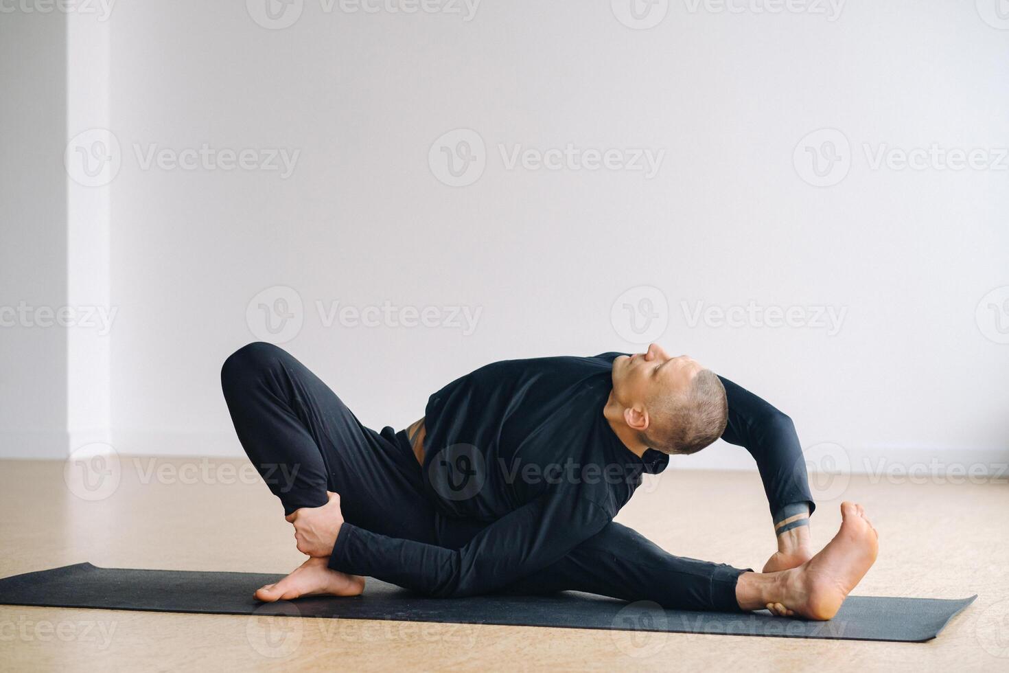 An athletically built man does yoga in the gym on a mat photo