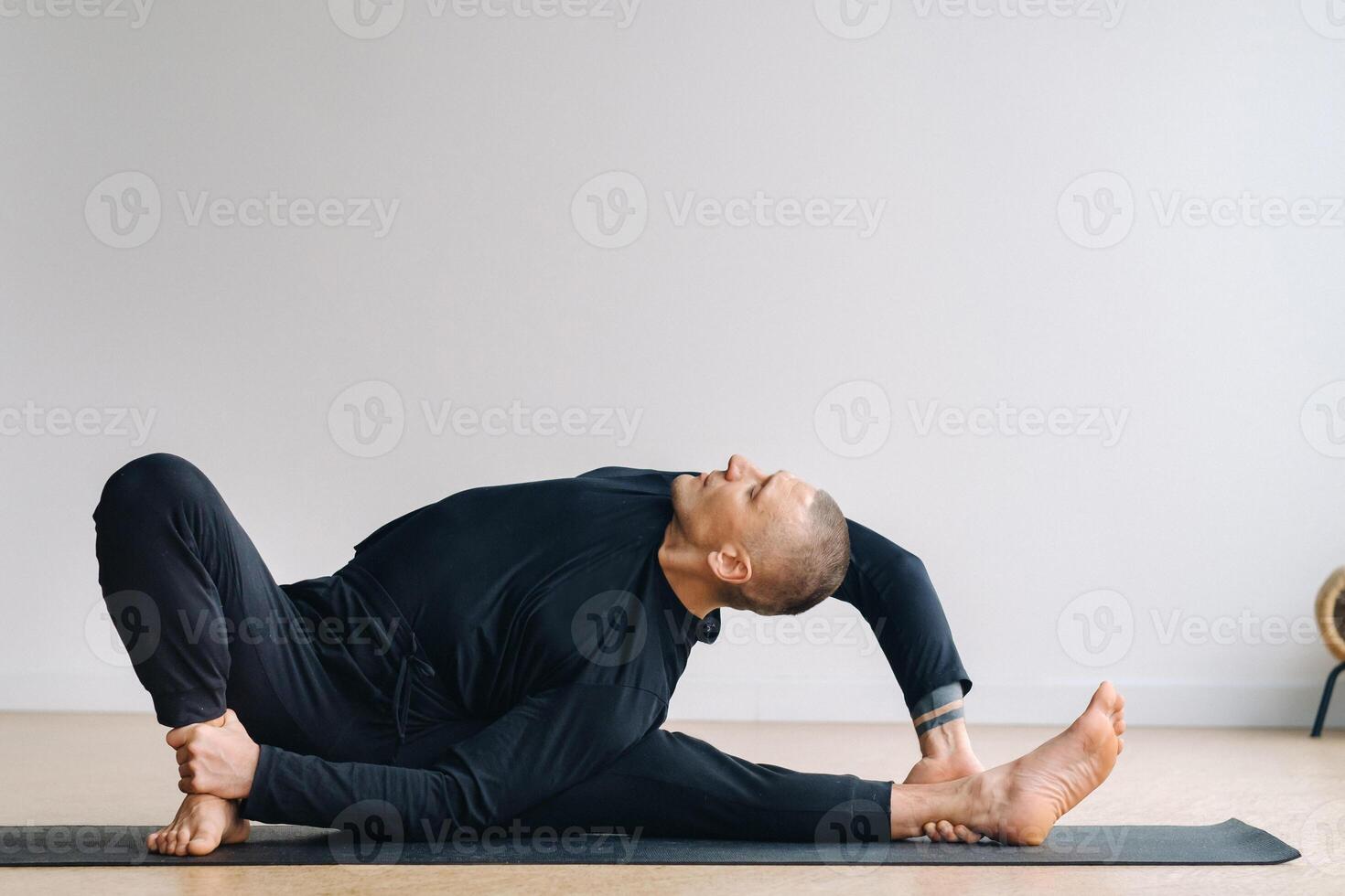 An athletically built man does yoga in the gym on a mat photo