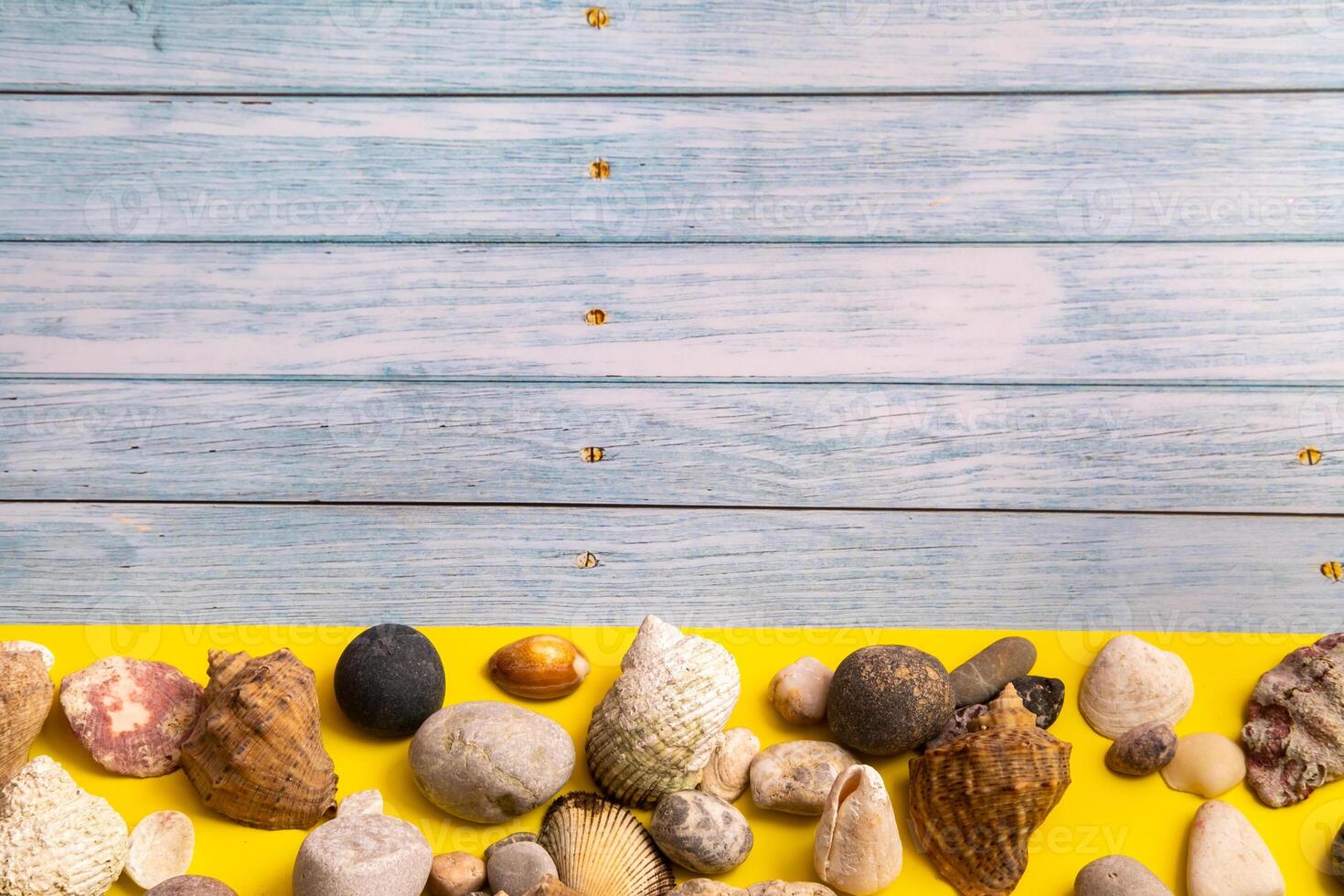 stones and shells on a blue wooden background and a yellow background.Marine theme photo