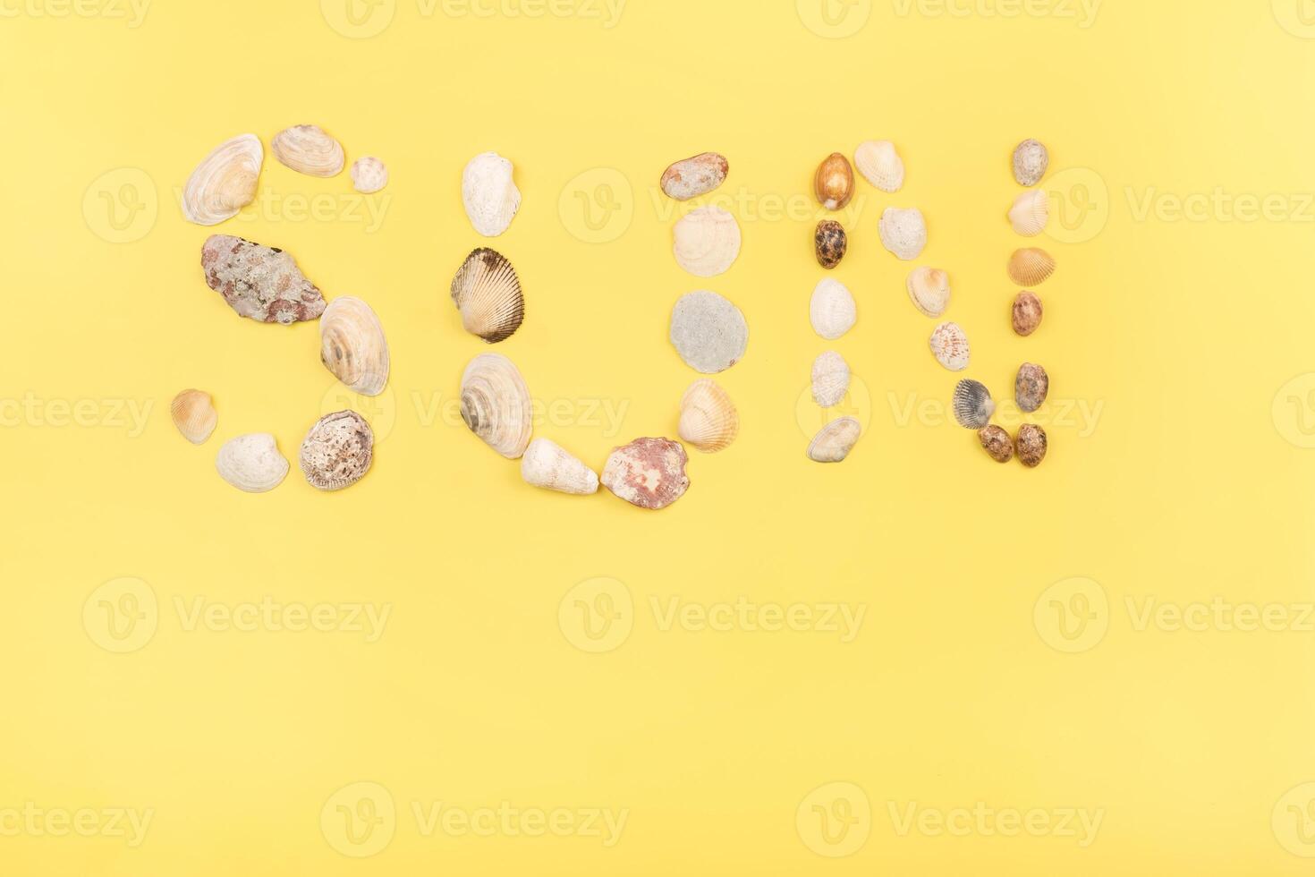 The inscription of the word sun is made of shells on a yellow background.Travel concept photo