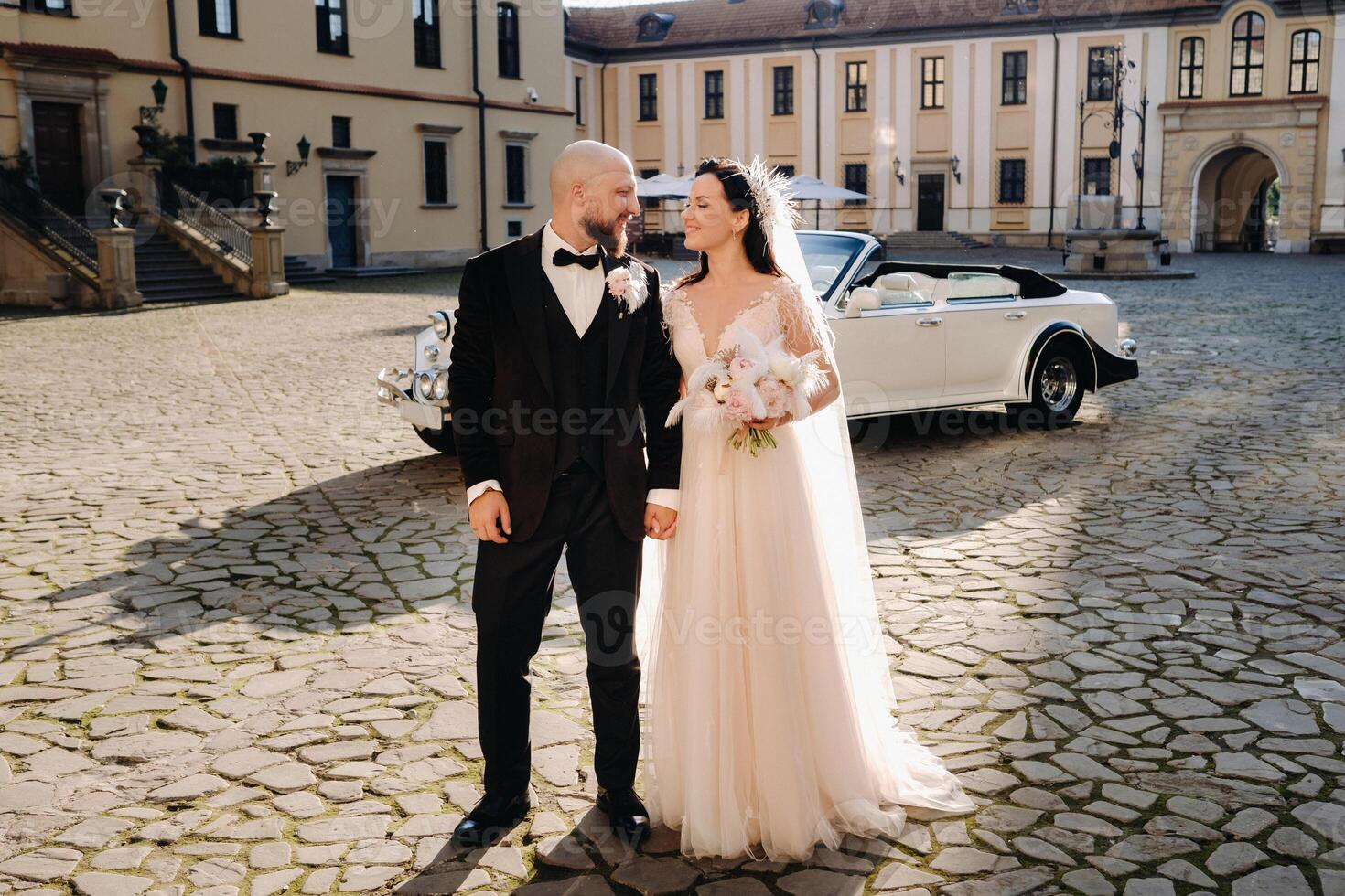 Elegant wedding couple In the courtyard of the castle near a retro car photo