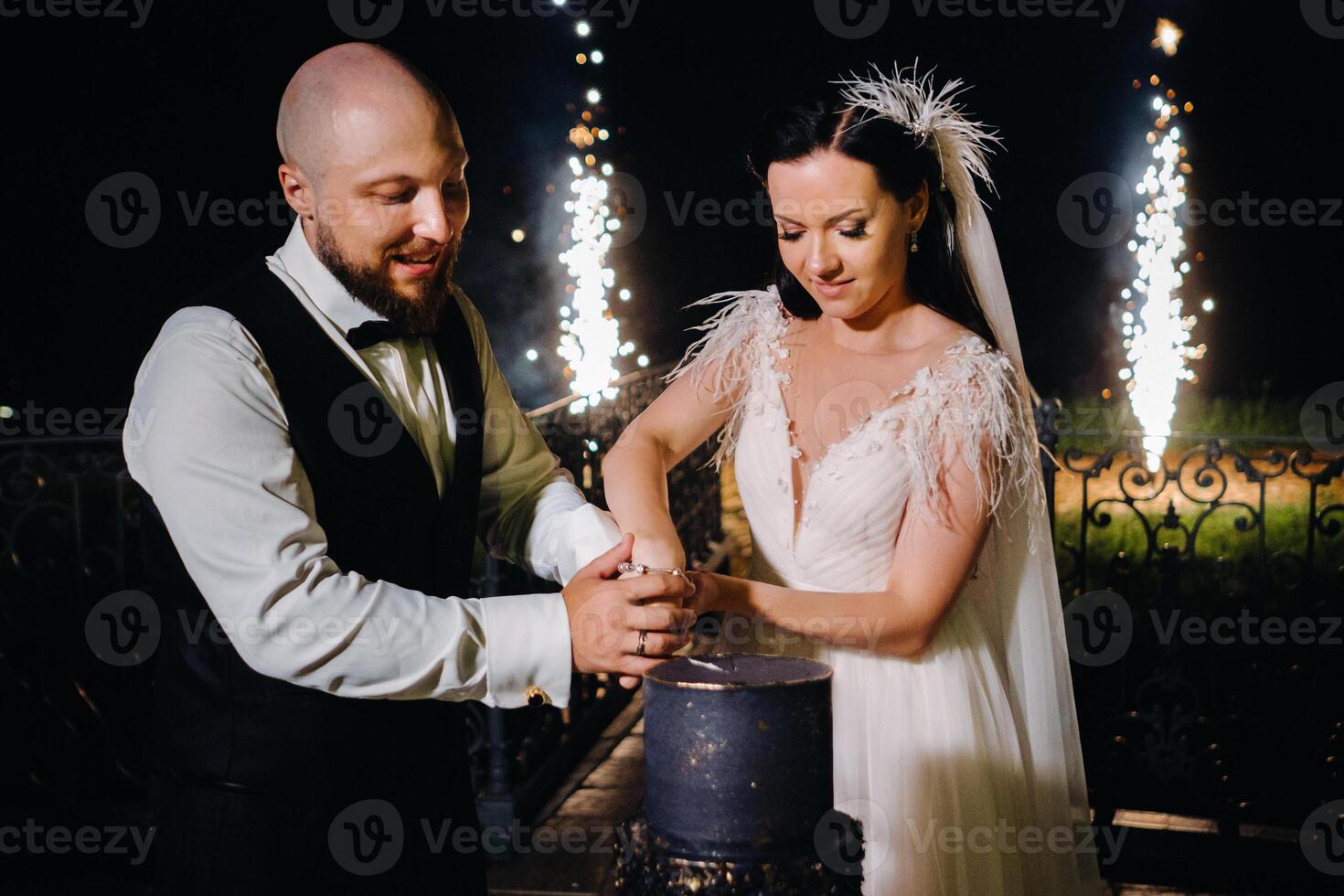 Stylish bride and groom cut the wedding cake in the evening on the street photo