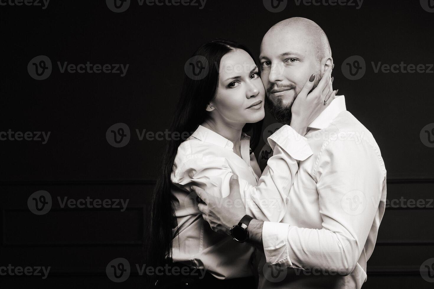 A man and a woman in white shirts on a black background.A couple in love in the studio interior.Black and white photo
