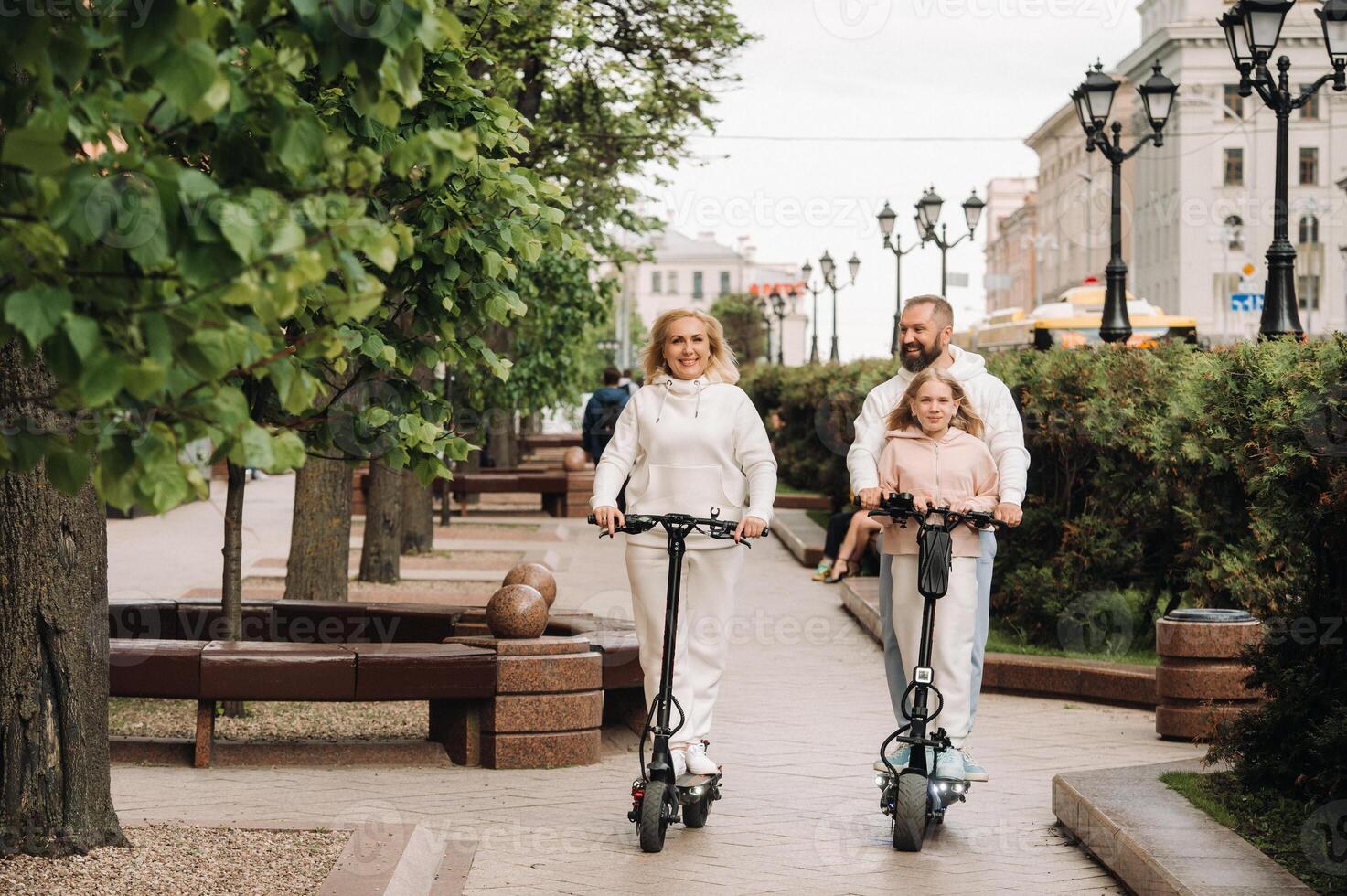 A family in white clothes rides electric scooters in the city.Outdoor activities photo