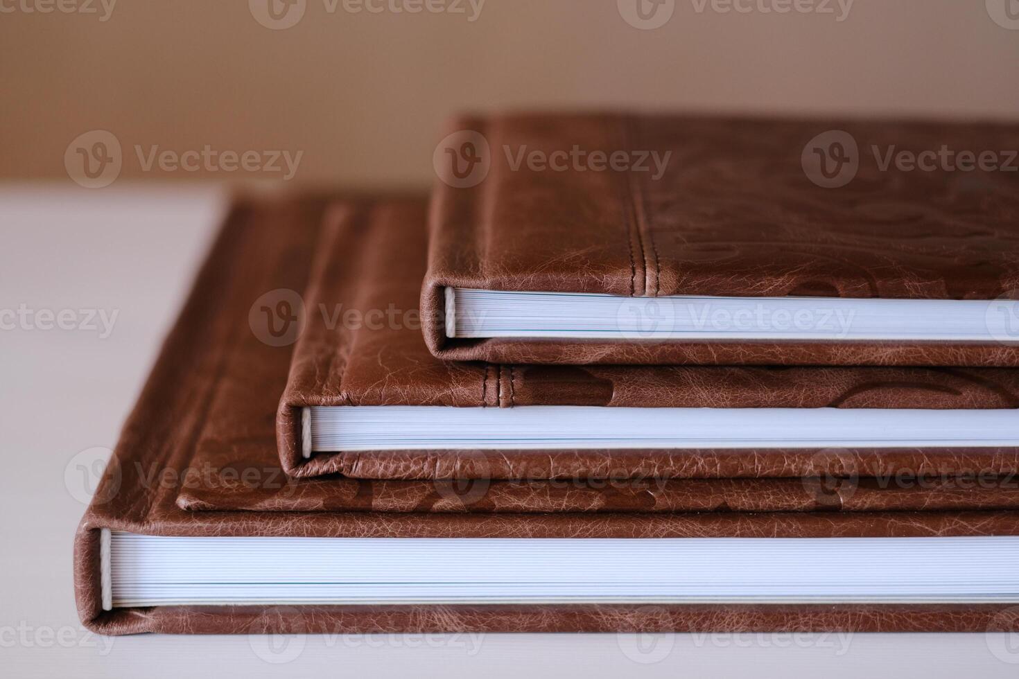 Composition of photo books in natural brown leather of different sizes. Fragment of a photobook binding