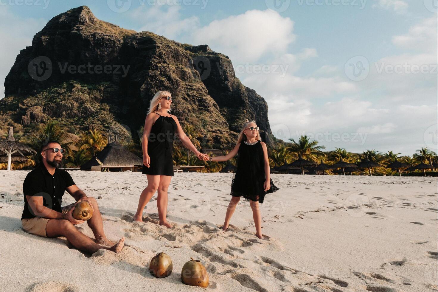 a stylish family in black clothes with coconuts in their hands on the beach of the island of Mauritius.Beautiful family on the island of Mauritius in the Indian ocean photo