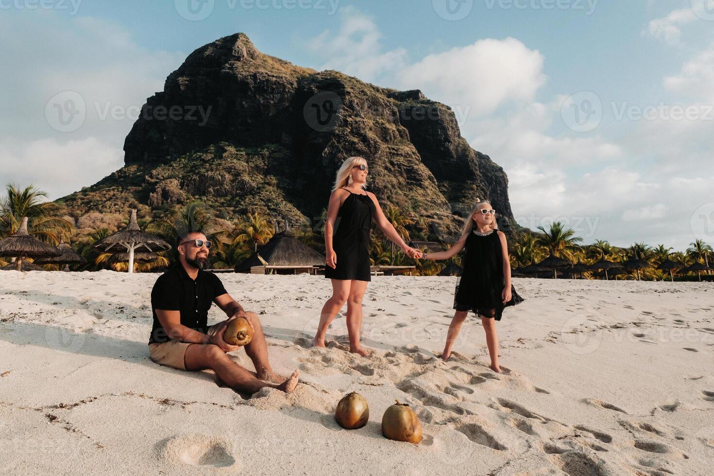 a stylish family in black clothes with coconuts in their hands on the beach of the island of Mauritius.Beautiful family on the island of Mauritius in the Indian ocean photo