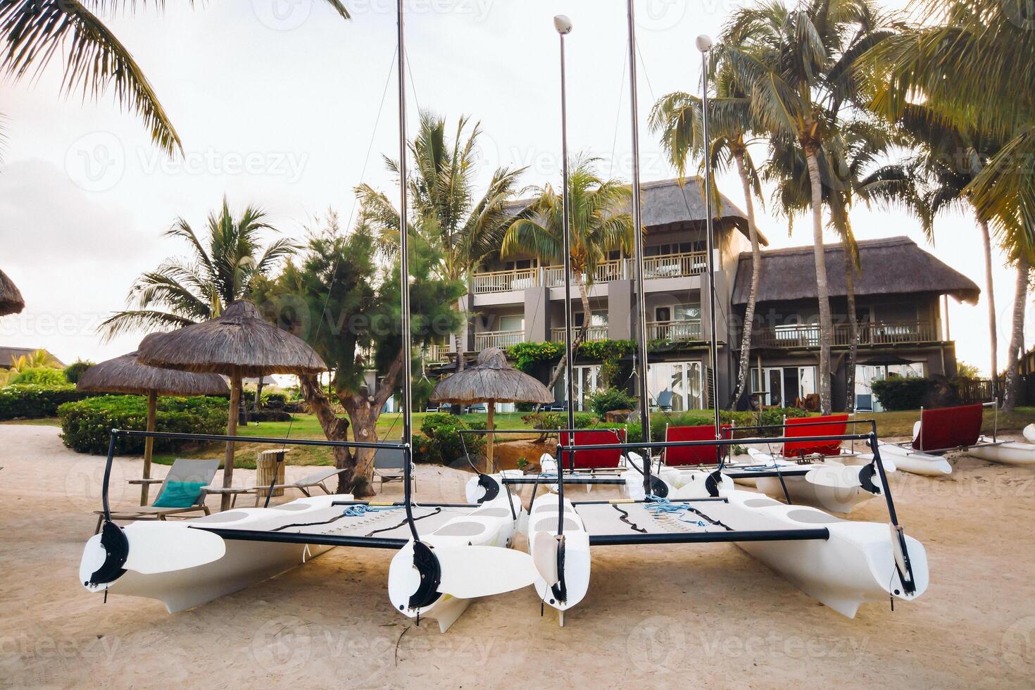 catamarans with sails are parked on the beach in front of a villa on the tropical island of Mauritius photo