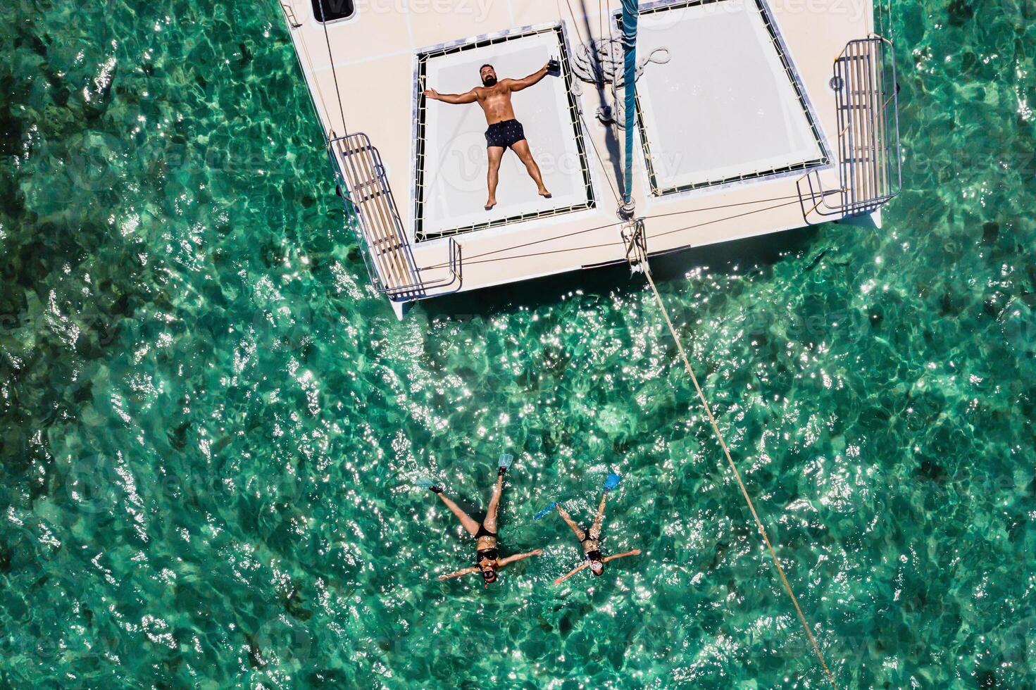 a young handsome man is lying on a yacht in the Indian ocean next to his family swimming in masks.Mauritius island photo