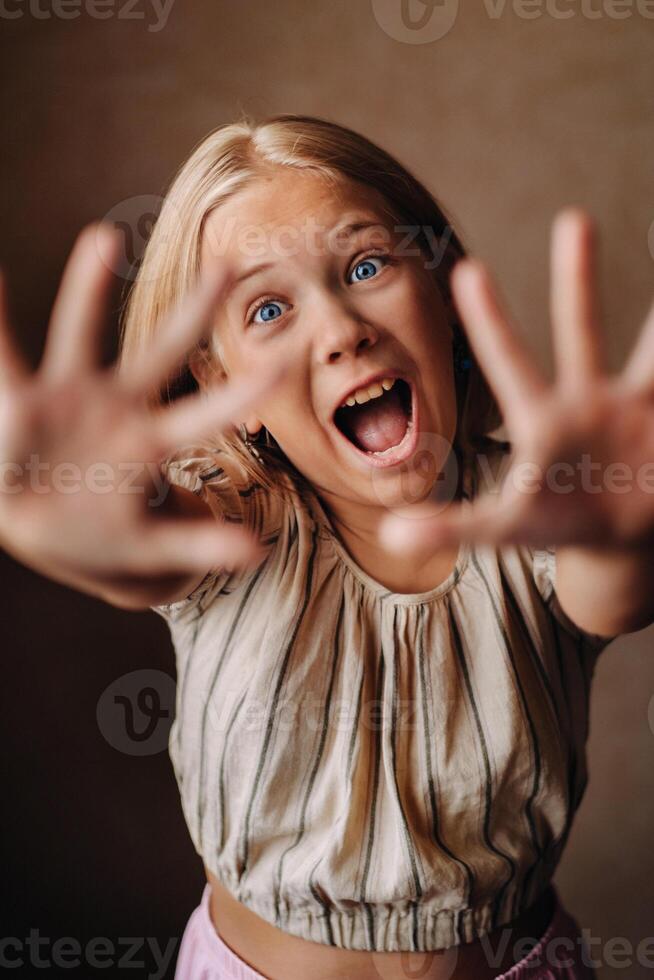 A happy child, a little girl in a gray T-shirt on a beige background photo