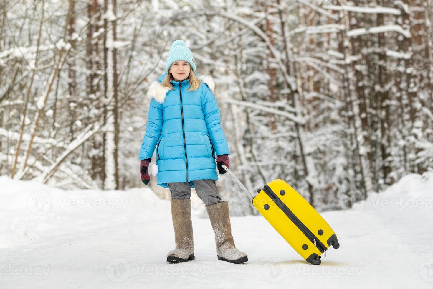 A girl in winter in felt boots goes with a suitcase on a frosty snowy day photo