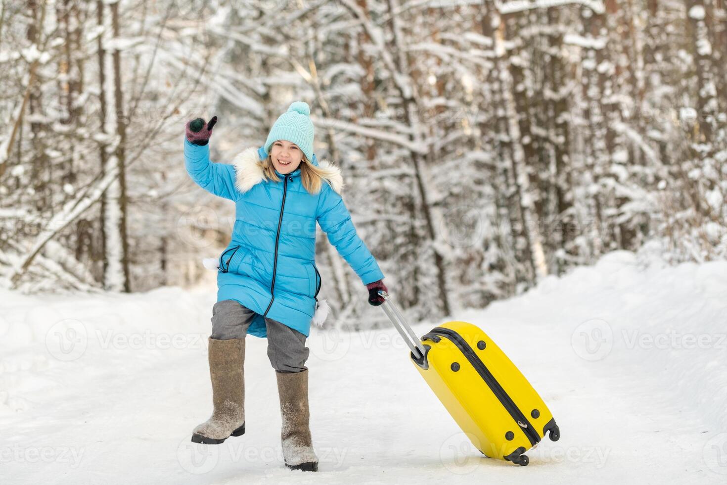 A girl in winter in felt boots goes with a suitcase on a frosty snowy day photo