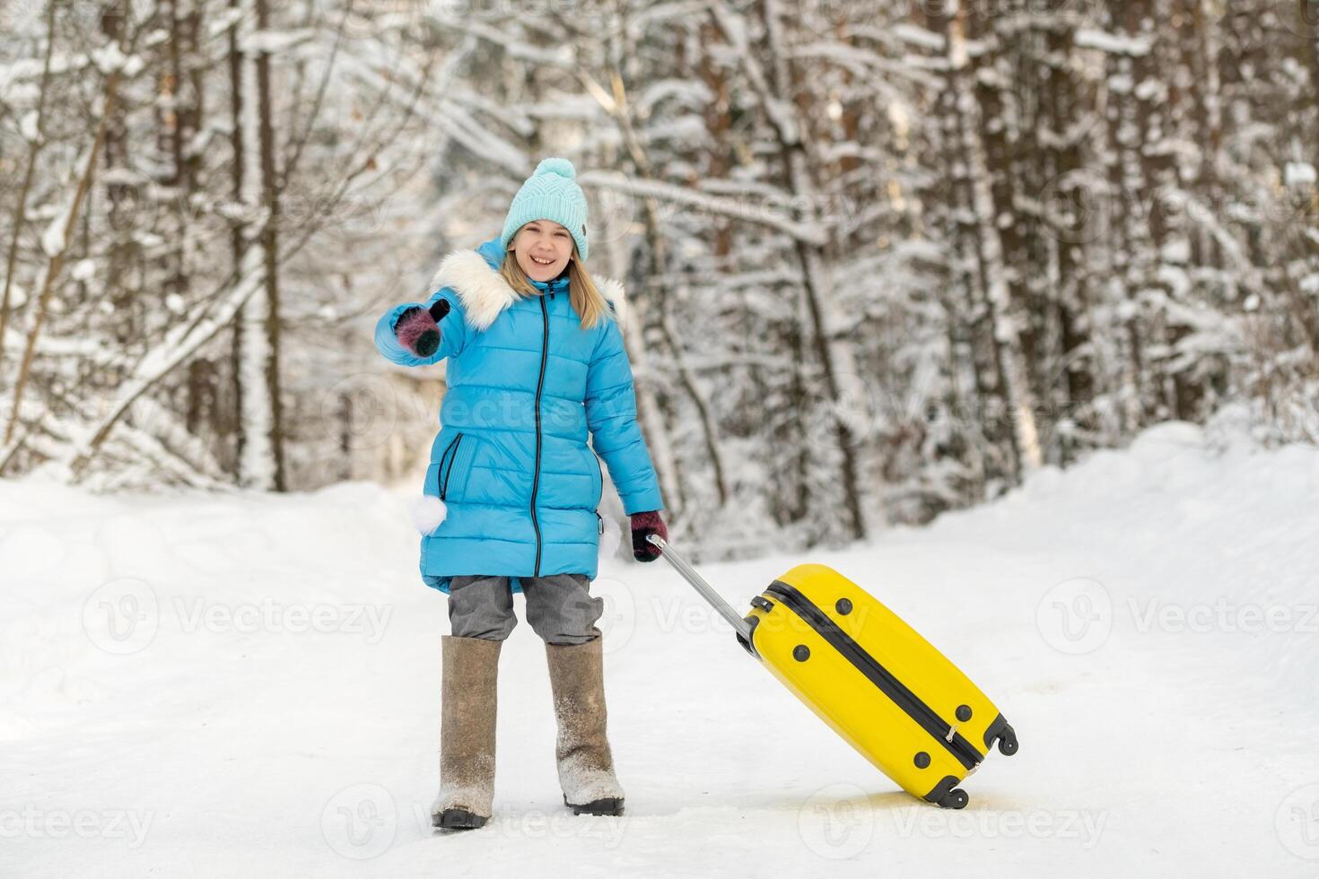 A girl in winter in felt boots goes with a suitcase on a frosty snowy day photo