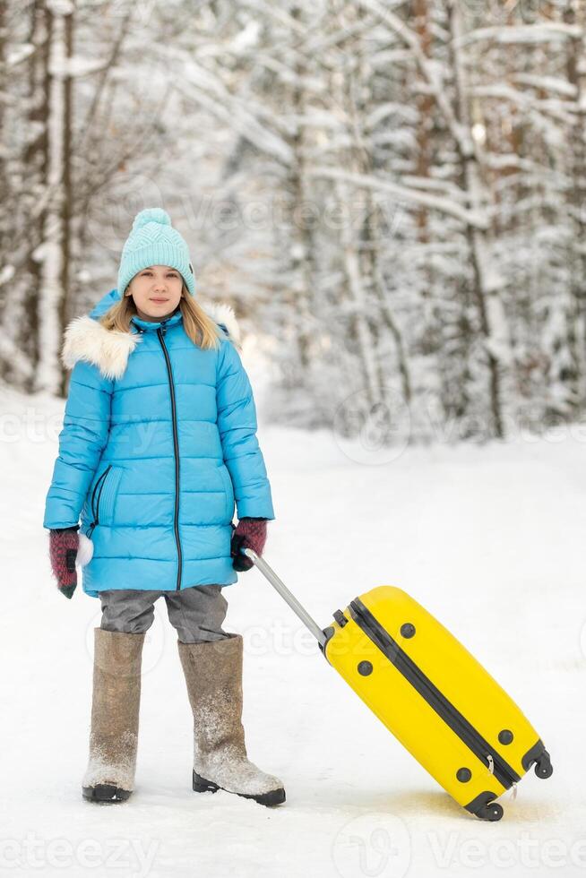 A girl in winter in felt boots goes with a suitcase on a frosty snowy day photo