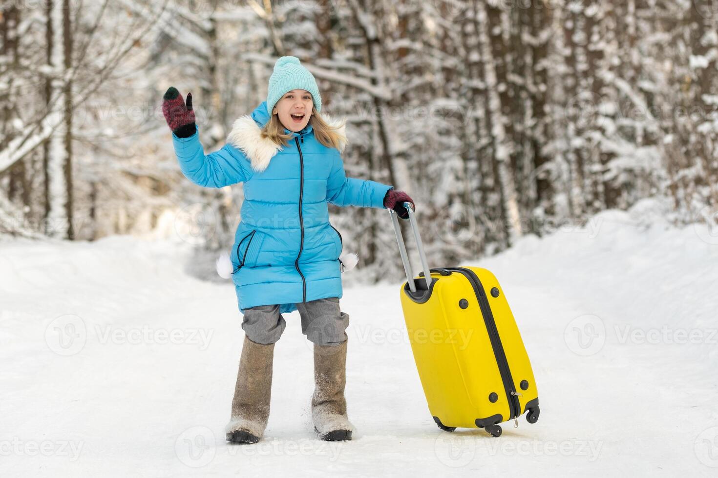 A girl in winter in felt boots goes with a suitcase on a frosty snowy day photo