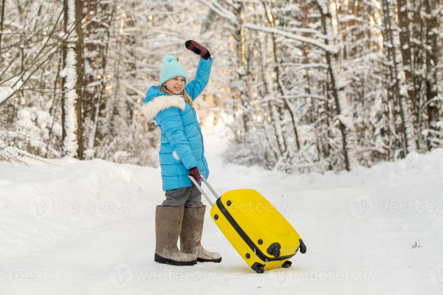 A girl in winter in felt boots goes with a suitcase on a frosty snowy day photo