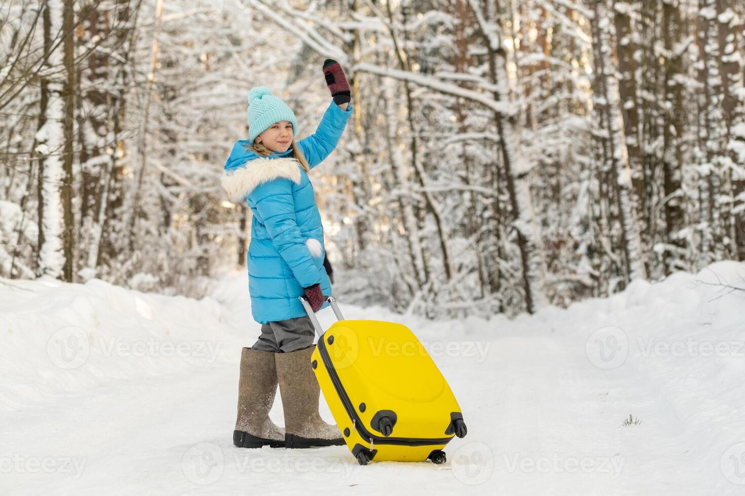 A girl in winter in felt boots goes with a suitcase on a frosty snowy day photo
