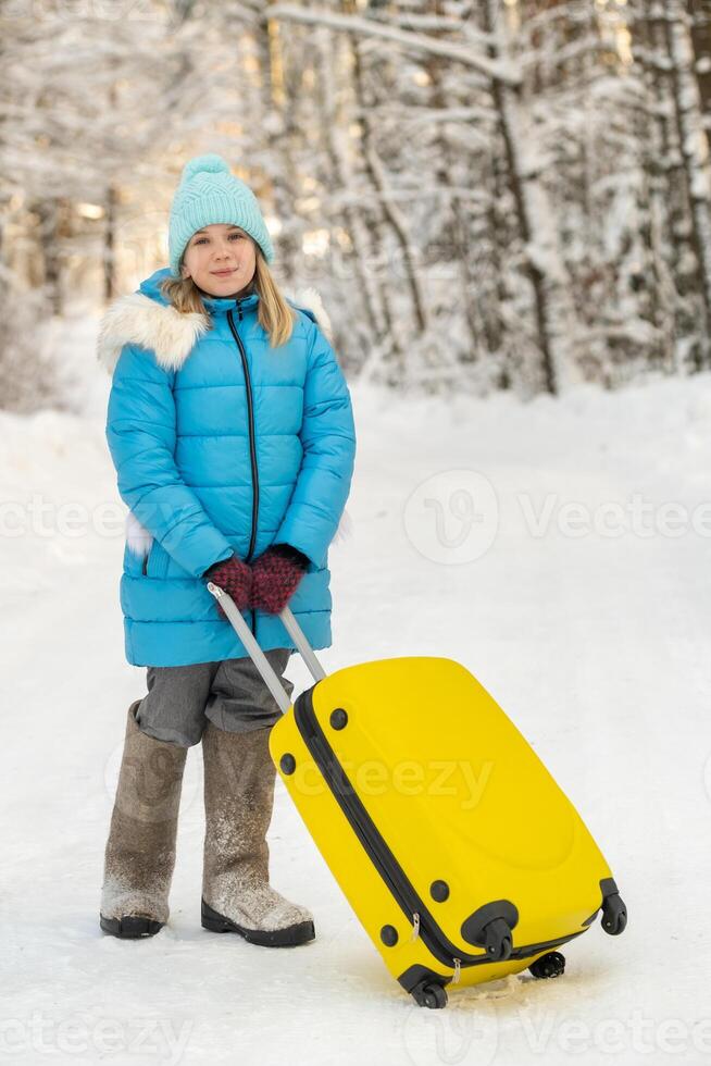A girl in winter in felt boots goes with a suitcase on a frosty snowy day photo