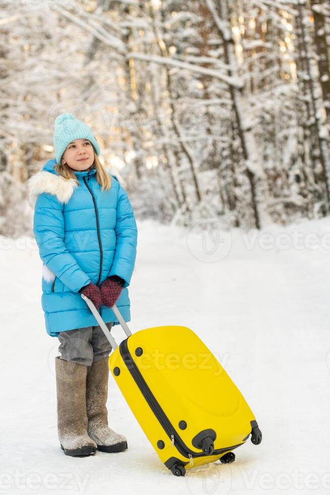 A girl in winter in felt boots goes with a suitcase on a frosty snowy day photo