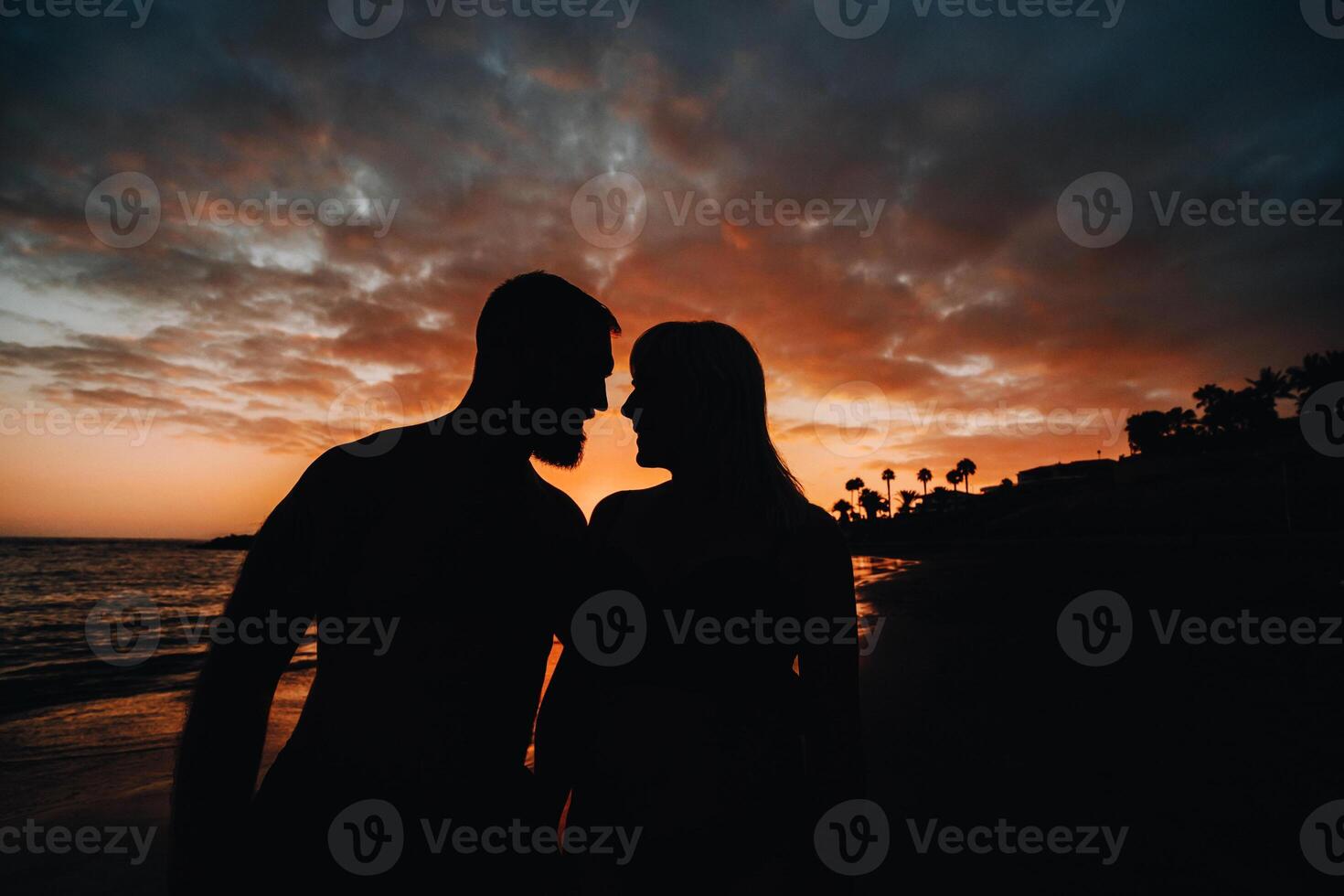 Romantic couple on the beach in a colorful sunset in the background.A guy and a girl at sunset on the island of Tenerife photo