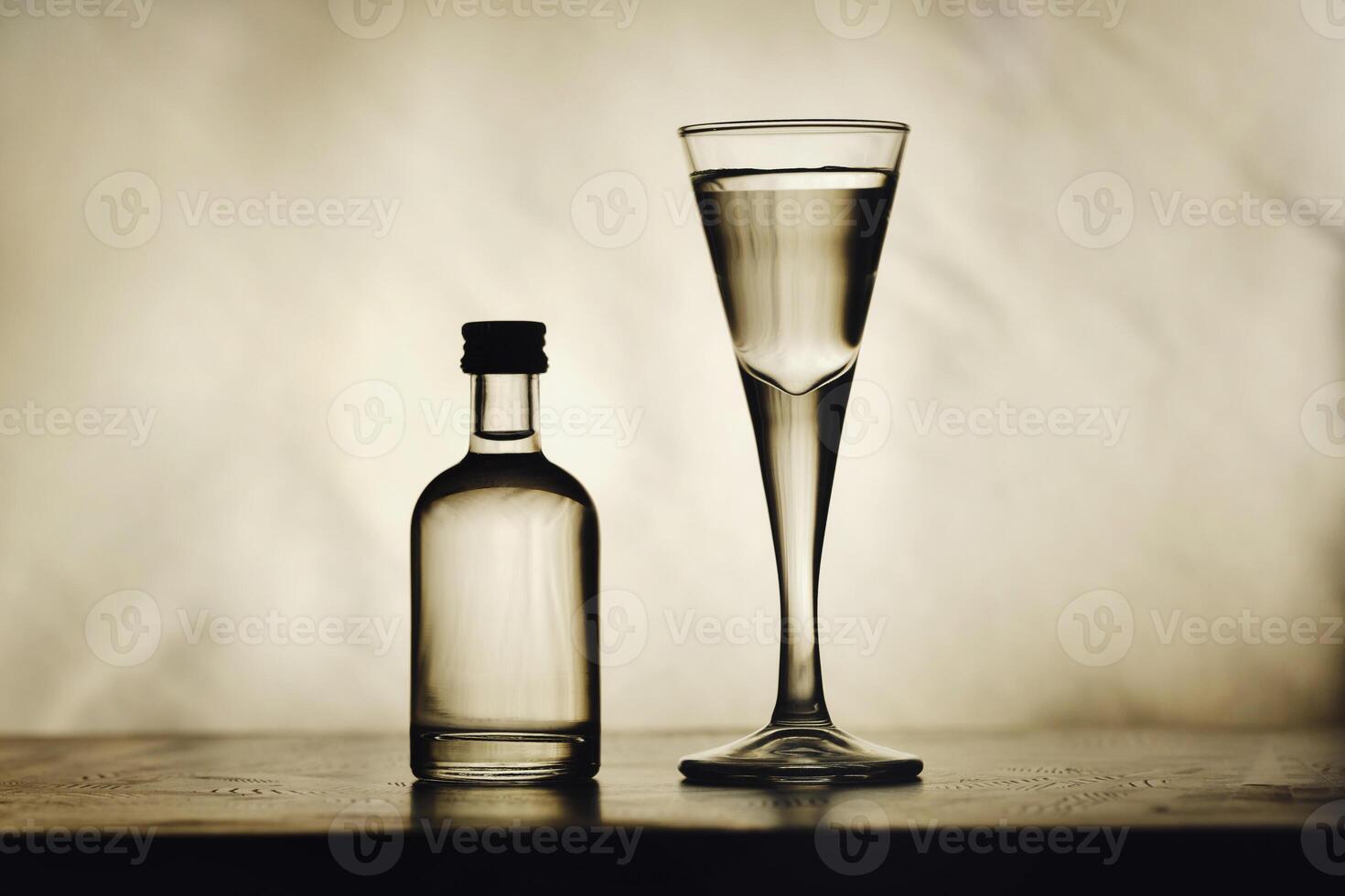 On the table are a bottle of alcohol and a full glass on a beautiful background photo