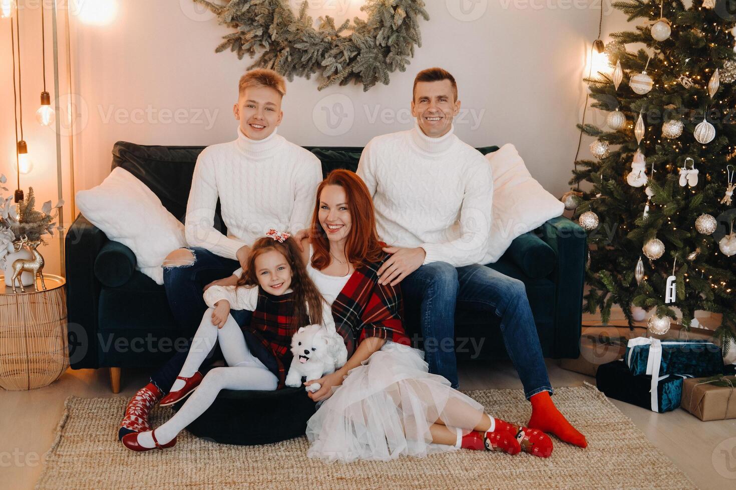 Close-up portrait of a happy family sitting on a sofa near a Christmas tree celebrating a holiday photo